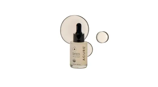 Szklana buteleczka z serum rozświetlającym ACURE z pipetką, na białym tle z kropelkami.