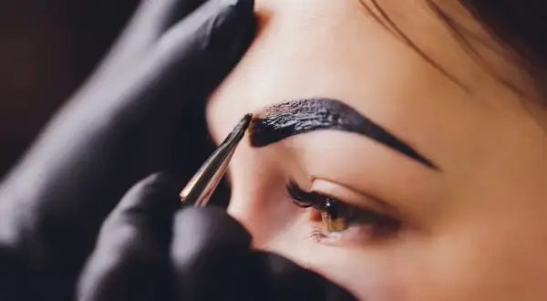Stylist nakłada hennę na brwi. Zastanawiasz się, ile kosztuje henna?